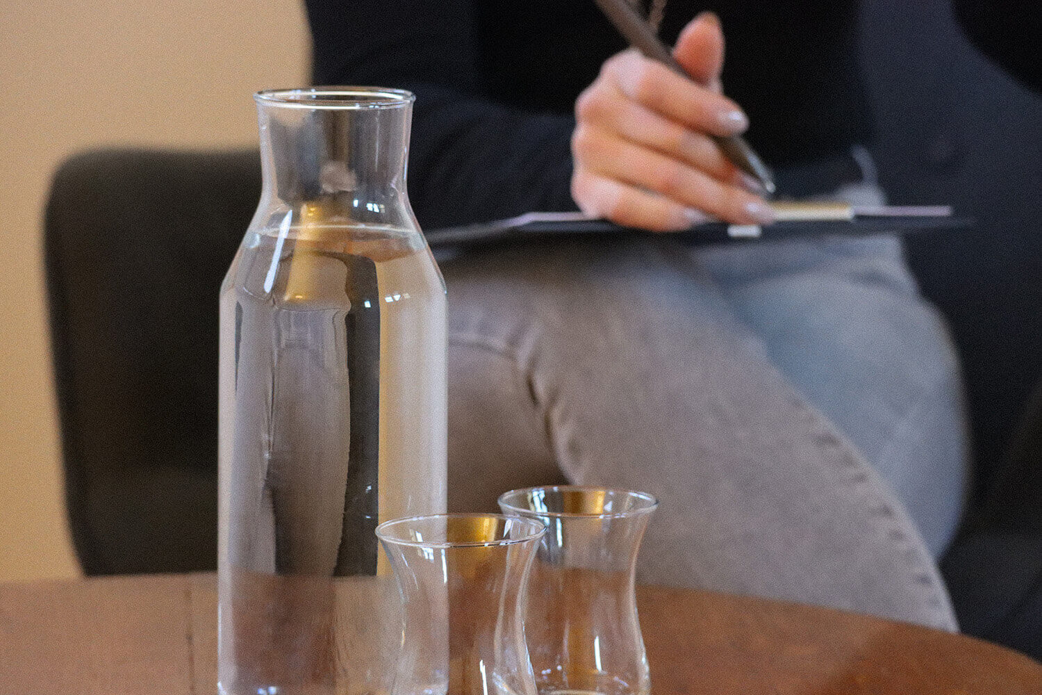 Tisch mit Wasserflasche, Gläsern und unscharfer Person.