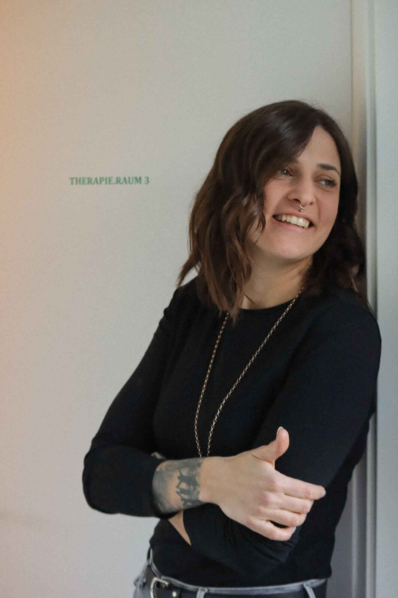 Lächelnde Kerstin Dörflinger neben Schild "THERAPIE RAUM 3".